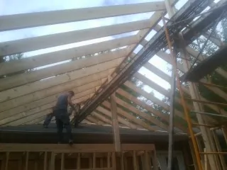 Rafters going up over a new addition with a worker on the wall in Circleville
