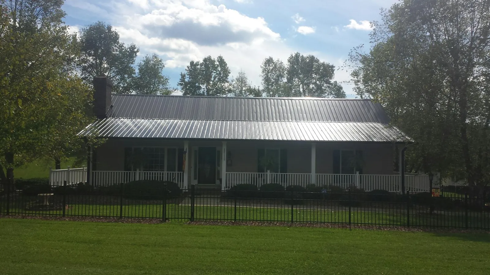 Gray metal roof on a brick ranch with a full width front porch — Gutter Guard Installation work by our crew in Circleville